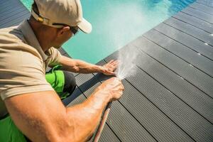 Men Washing His Swimming Pool Deck Using Garden Hose photo