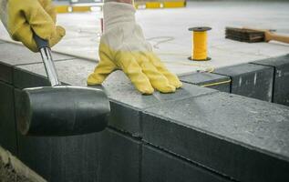 Worker Levelling Patio Concrete Floor Bricks Close Up photo