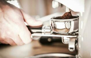 Male Grinding Coffee In Barista Machine. photo