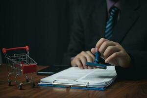 Man hand stamping approval signing on document or paperwork contract at desk. photo