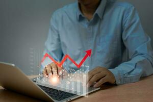 Businessman using laptop computer graph stock market and chart marketing investment financial with arrow red, interest rates and dividends, income, retirement. photo