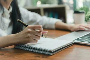 Woman hand with notebook for planning with laptop computer and documents.Freelance career, information and strategy and journal report. photo