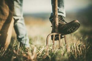 Cowboy Rancher Resting His Leg on a Garden Fork photo