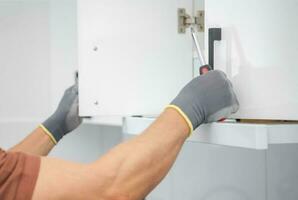 Cabinetmaker Finishing Installation of a New Kitchen Cabinets photo