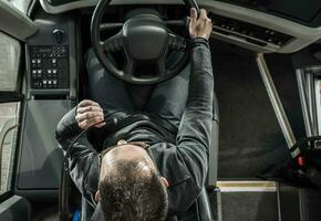 Coach Bus Driver Behind the Vehicle Talking to Vehicle Intercom Wheel Top View photo