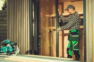 Contractor Installing Aluminium Frame Window Glass Doors Inside a Shed photo