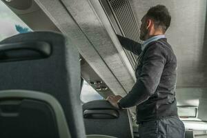 International Coach Bus Passenger Securing Luggage Inside Vehicle photo