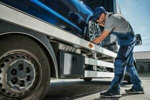 Professional Tow Truck Driver Fastening the Car for Safe Transportation photo