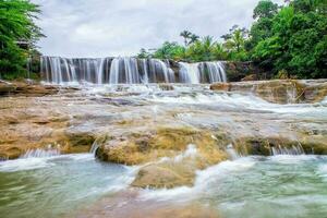 The beautiful deng deng waterfall flows in a wide river in tasikmalaya, west java, indonesia photo