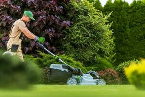 Garden Worker with Grass Mower Working in Residential Garden photo