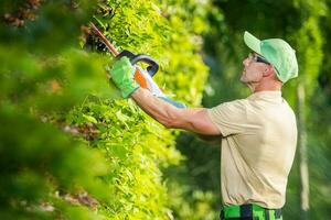 jardinero con eléctrico sin cable cobertura recortadora en acción foto