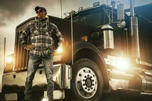 Professional Truck Driver Proudly Standing in Front of His Heavy Duty Vehicle photo