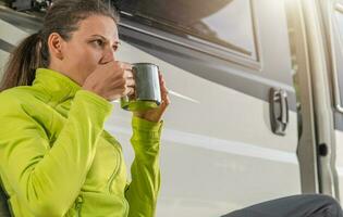 Woman Drinking Cup of Hot Coffee in Front of Her Camper Van photo