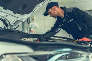 Mechanic Looking Under Car Hood photo