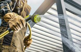 Men Watering His Backyard Lawn Using Garden Hose photo