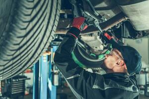 Mechanic Fixing Chassis Of Car In Garage. photo