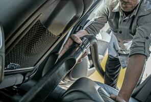caucásico hombres Pasar la aspiradora coche interior a mantener vehículo limpio. foto