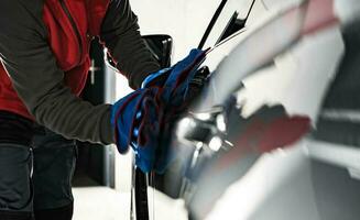 Car Wash Worker Detailing Vehicle Body Using Soft Cloth photo