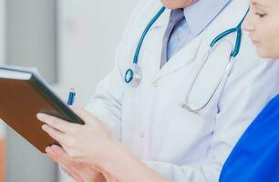 Doctor Signing Papers Held By Nurse. photo