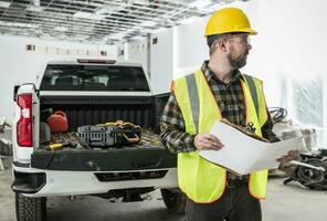 Construction Supervisor with Blueprints in His Hand Next to Pickup Truck Inside Commercial Building photo