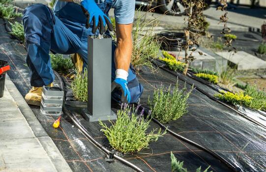 Landscaping Worker Installing Bulb Inside Small Garden Light Post photo