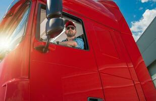 Professional Trucker Behind the Semi Tractor Truck Wheel photo