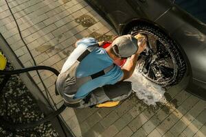 Worker Cleaning Modern Vehicle Alloy Wheels photo