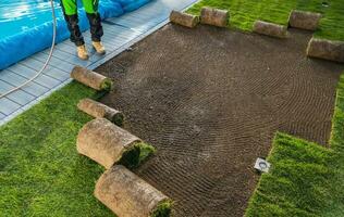 paisajismo trabajador laminación fuera césped rollos en un jardín foto