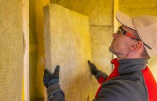 Insulation Contractor Installing High Temperature Mineral Wool Inside House Walls. photo