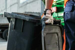 Garbage Truck Worker Moving Trash Can photo