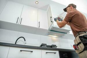 Contractor Worker Assembling of New Apartment Kitchen Cabinets photo