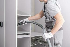 Man Vacuuming Shelving In Walk In Closet. photo