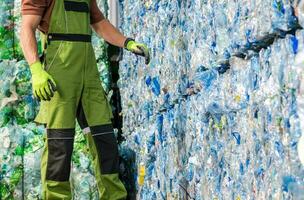 Waste Management Worker in Front of a Pile of Pressed Plastic PET Bottles photo