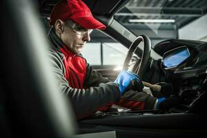 Automotive Detailing Worker with Soft Brush Inside a Car photo