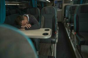 Tired Businessman Sleeping on Coach Bus Table photo