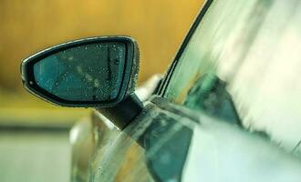 Clean and Still Wet Modern Vehicle Mirror After Car Wash Cleaning photo