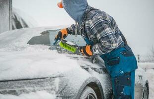 Men Removing Snow From His Vehicle and Deicing Windshield. photo