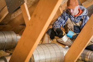 Male Contractor Binding Ventilation Pipes With Duct Tape. photo