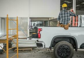 Construction Contractor Worker Taking Short Brake Seating on His Pickup Truck Cargo Bed photo