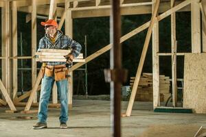 Construction Worker Moving Pieces of Wood Inside Wooden Skeleton Frame of a House photo