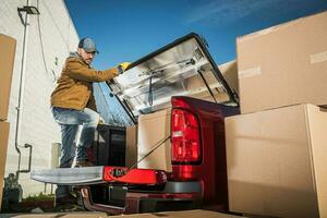 Professional Mover Loading Boxes on His Pickup's Cargo Bed photo