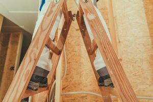 Construction Worker Staying on Wooden Ladder photo