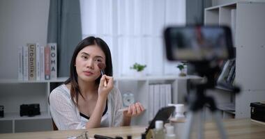 Beautiful young Asian woman blogger shows how to make up cosmetics at home photo