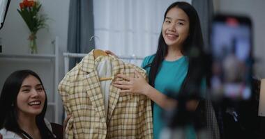 Young Asian female fashion designer using mobile phone live steaming photo