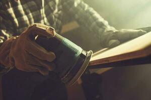 Worker Softening Plank Edges Using Wood Sander photo