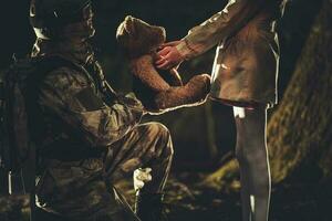 Soldier Giving Teddy Bear Toy to Caucasian Girl photo