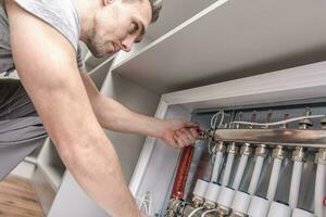 Men Adjusting Apartment Heat on the Central System Valves photo