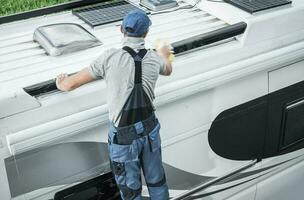 RV Service Worker Cleaning Camper Van Roof photo