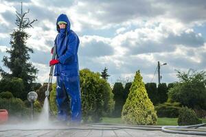 masculino jardinero limpieza acera con alto presión equipo. foto
