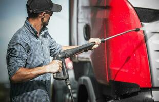 Truck Driver Washing His Vehicle Using Pressure Washer photo